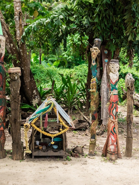 Colorful carved wooden totems and small shrine in Surin Islands village setting.