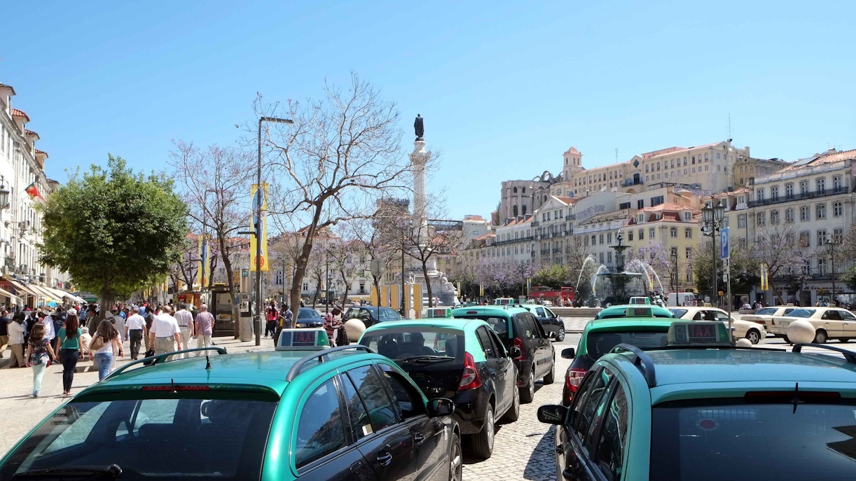 Lisbon taxis lined up near Rossio Square with historic buildings in the background.