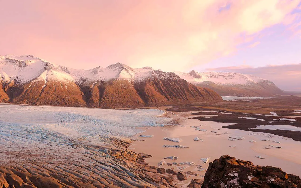 Mountains and glacier at sunset during Flyover Iceland experience.