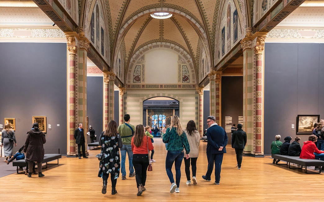 Visitors exploring the Rijksmuseum's ornate gallery during a guided tour in Amsterdam.
