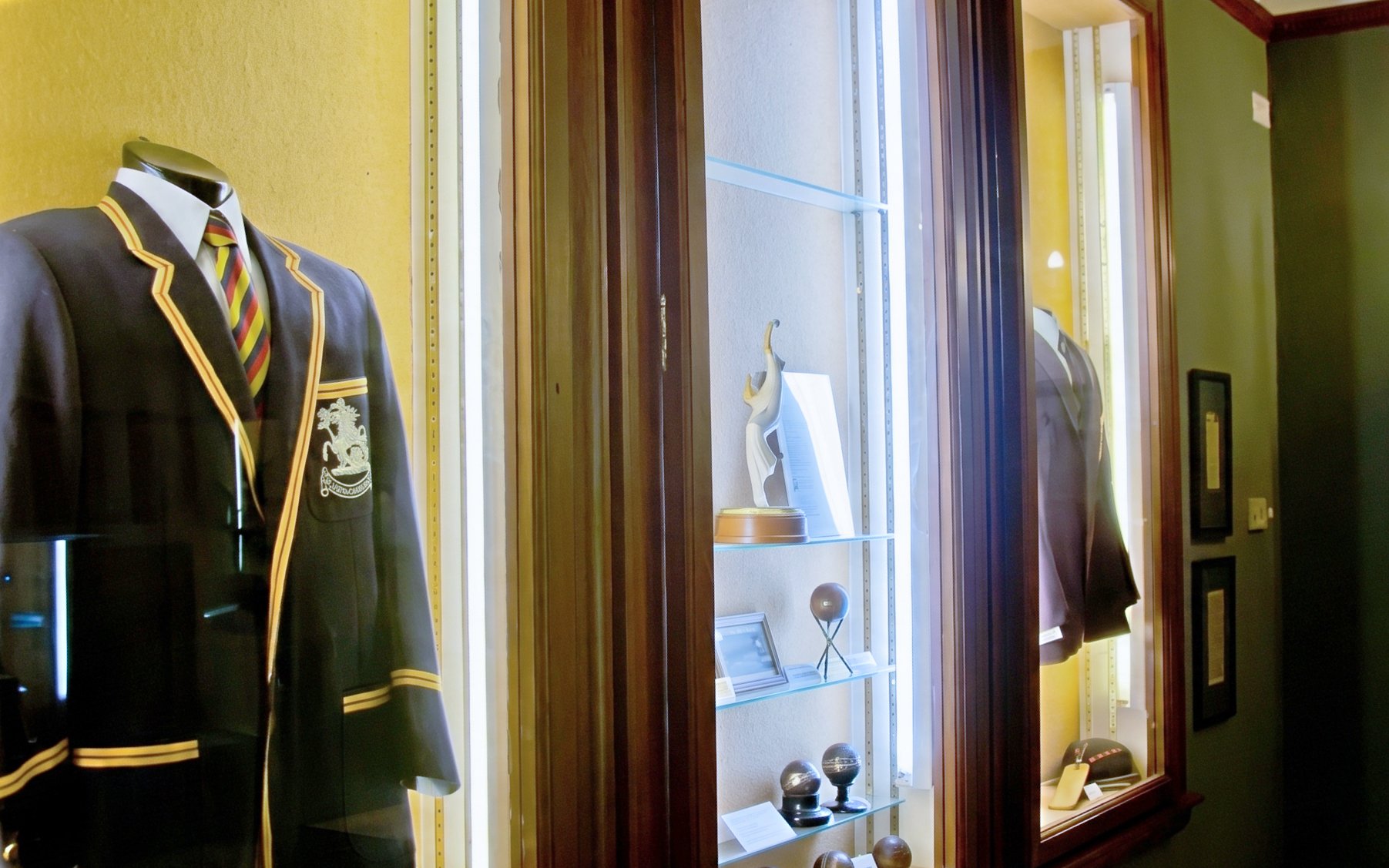 Cricket memorabilia display at Kia Oval Stadium, including blazers and trophies.