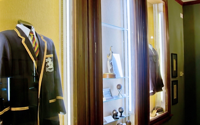 Cricket memorabilia display at Kia Oval Stadium, including blazers and trophies.