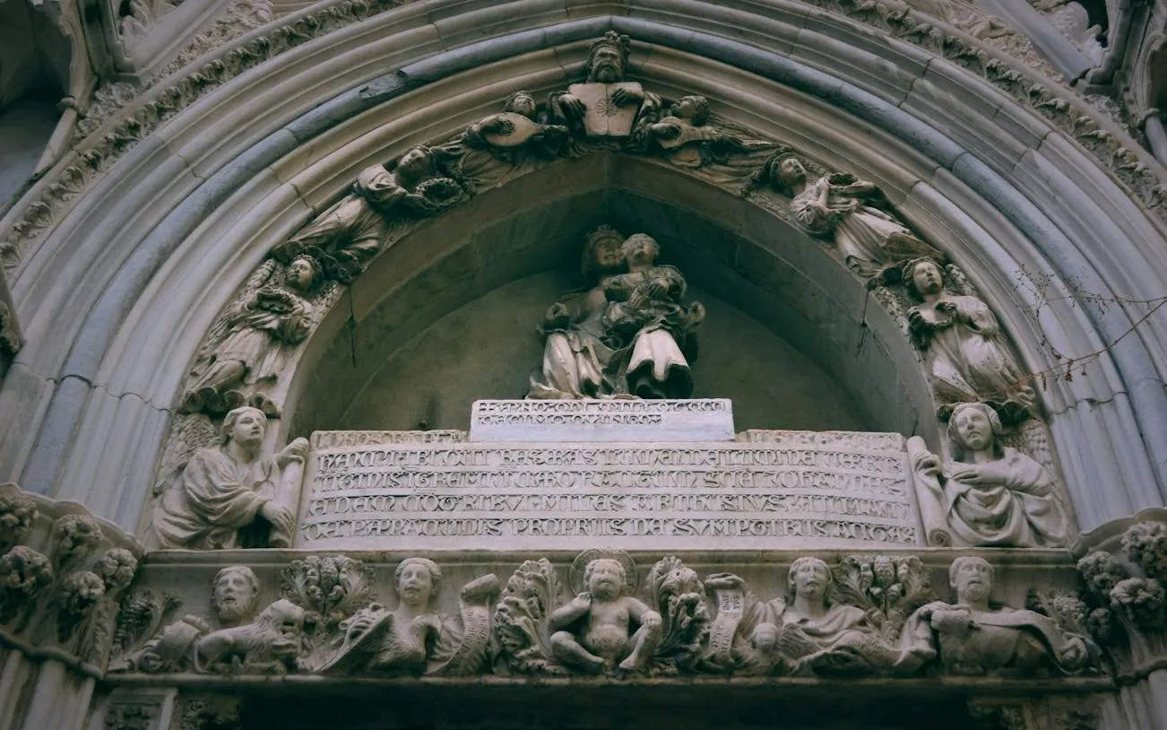 Stone carvings on a historic archway in Naples, featuring religious figures and inscriptions.