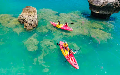 Kayakers paddling near rock formations in clear waters at Khlong Rood, Krabi.