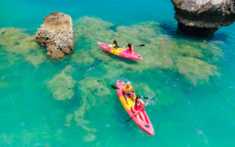 Kayakers paddling near rock formations in clear waters at Khlong Rood, Krabi.