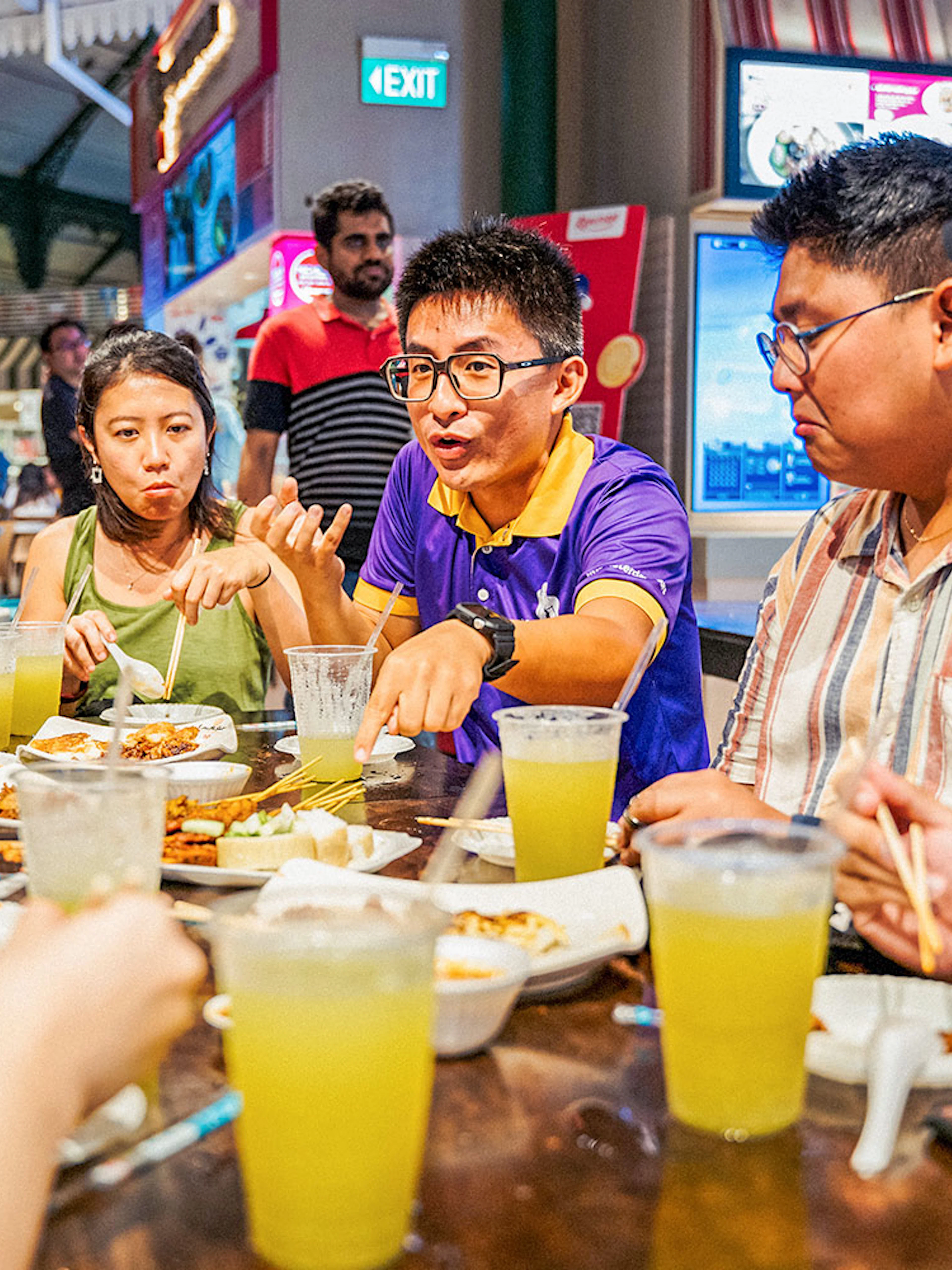 Group enjoying Singapore street food at a night market table.