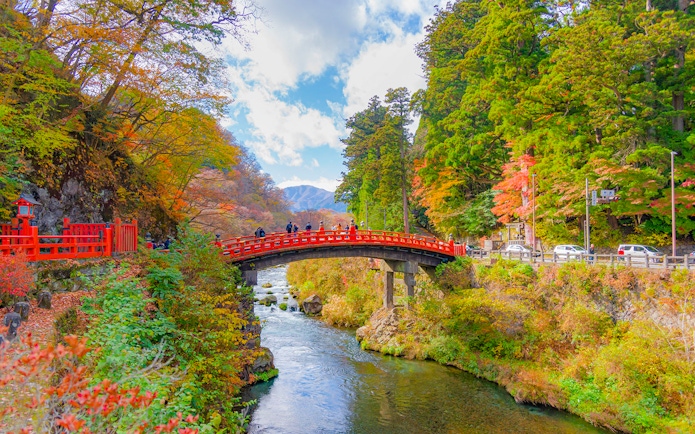Shinkyo Bridge over a river surrounded by autumn foliage in Nikko, Japan.