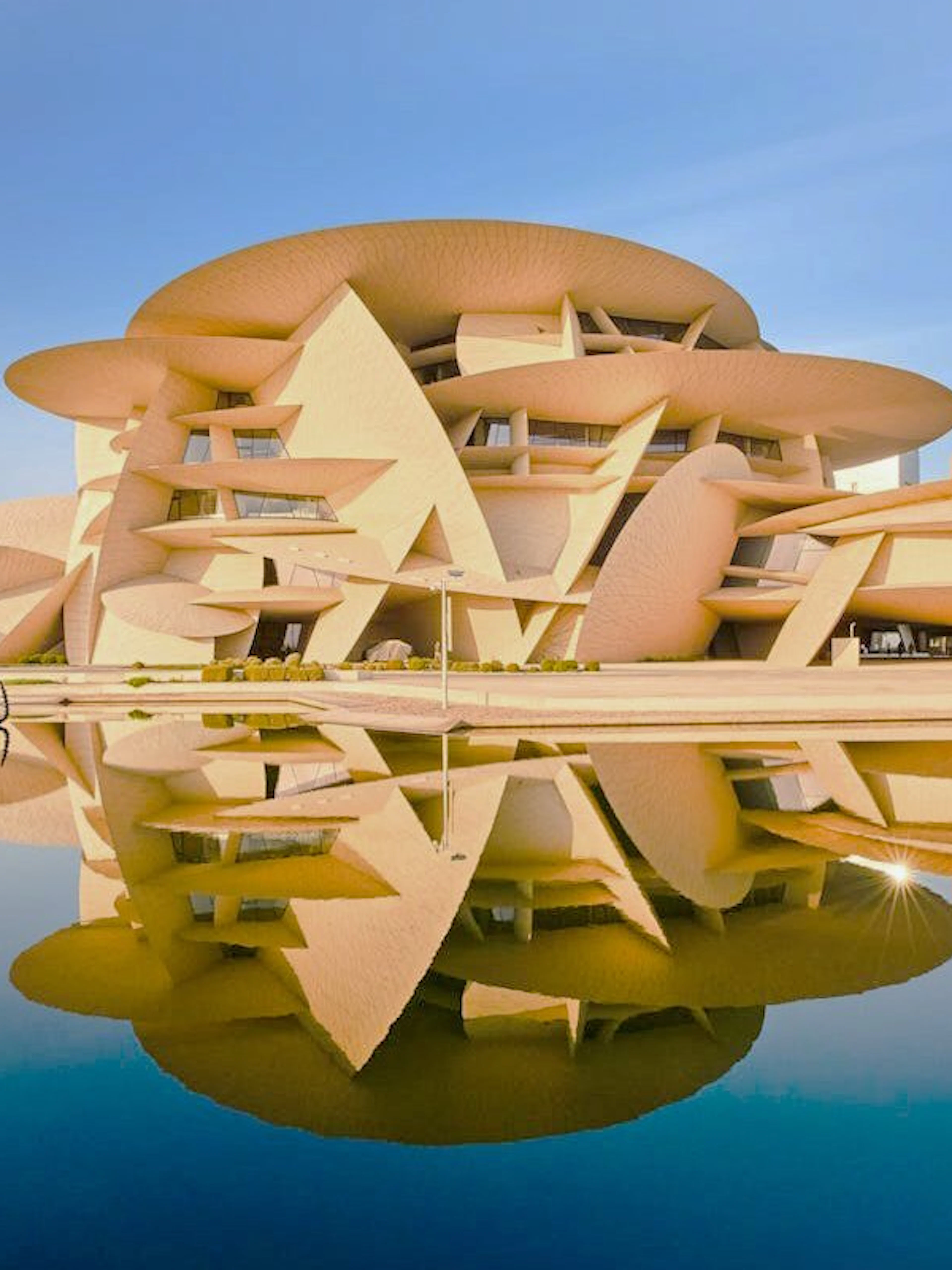 National Museum of Qatar in Doha with unique architecture reflected in water.