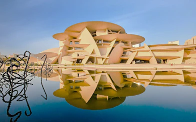 National Museum of Qatar in Doha with unique architecture reflected in water.