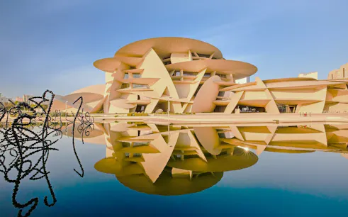 National Museum of Qatar in Doha with unique architecture reflected in water.