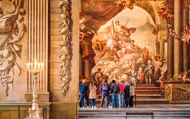 Visitors admiring the grand mural in the Painted Hall, Old Royal Naval College, London.