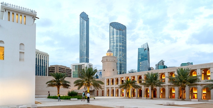 Qasr Al Hosn courtyard with modern skyscrapers in Abu Dhabi background.