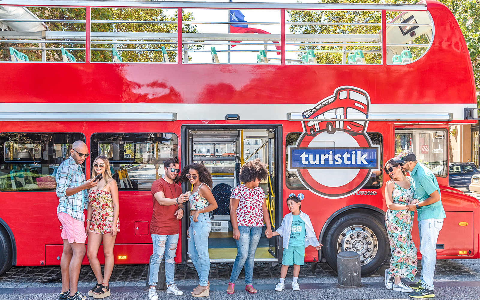 Tourists standing by a red Santiago hop-on hop-off bus, enjoying the city tour.