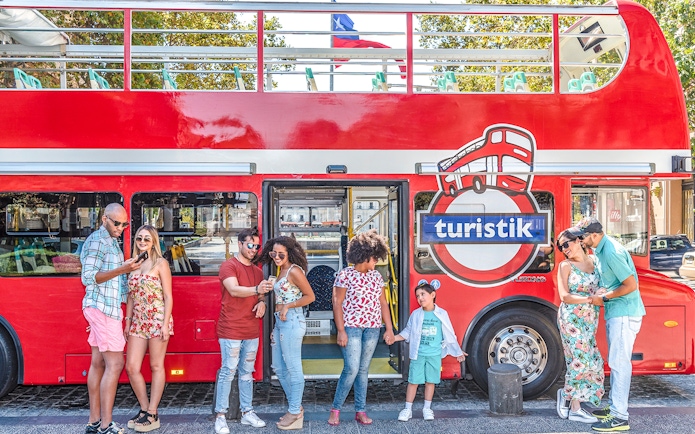 Tourists standing by a red Santiago hop-on hop-off bus, enjoying the city tour.