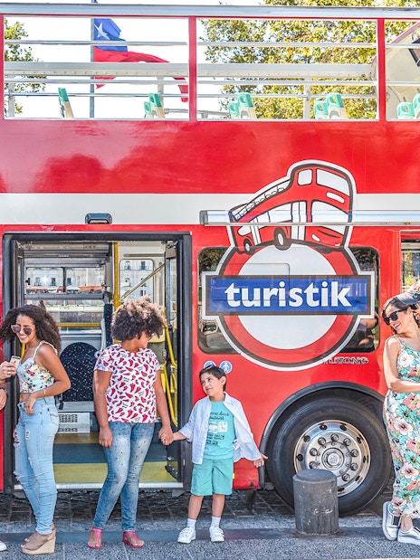 Tourists standing by a red Santiago hop-on hop-off bus, enjoying the city tour.