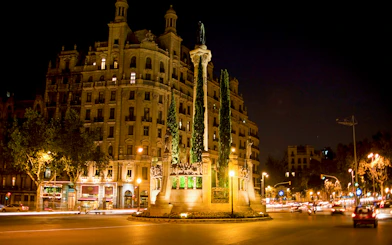 Barcelona night tour featuring illuminated historic building and monument in city square.