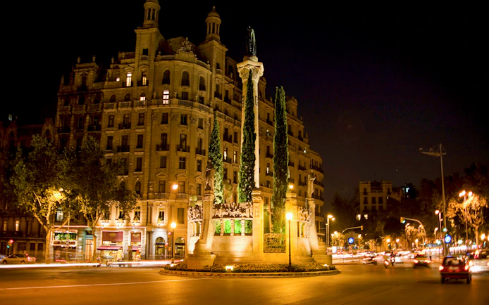 Barcelona night tour featuring illuminated historic building and monument in city square.