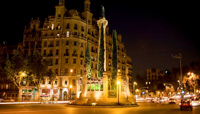 Barcelona night tour featuring illuminated historic building and monument in city square.