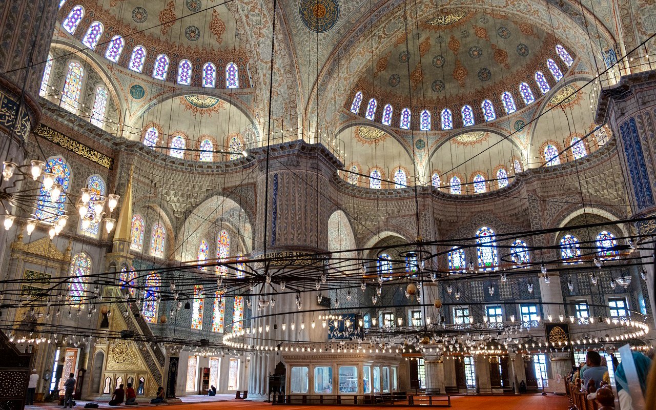 Interior of the Blue Mosque in Istanbul with ornate domes and stained glass windows.