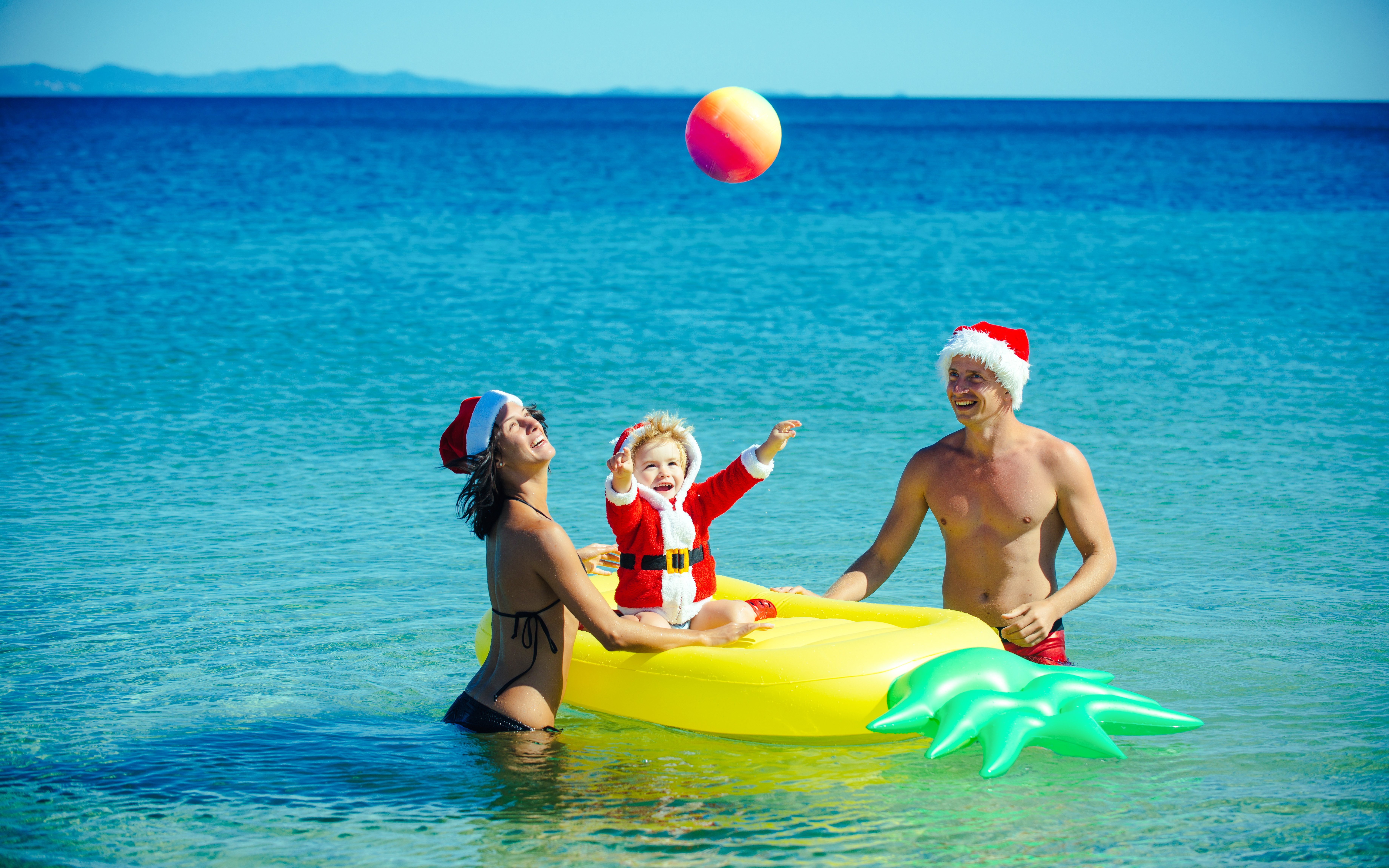 Family enjoying Christmas at Miami Beach with Santa hats and inflatable float.