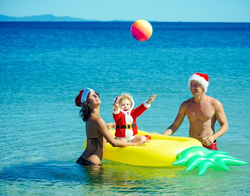 Family enjoying Christmas at Miami Beach with Santa hats and inflatable float.