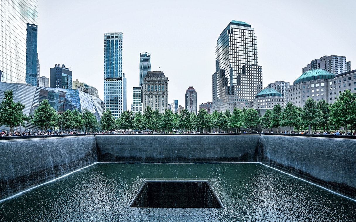 9/11 Memorial waterfall with city skyline in New York City.