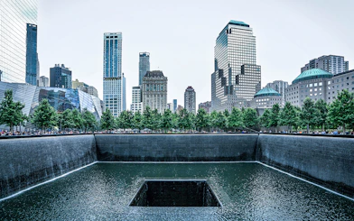 9/11 Memorial waterfall with city skyline in New York City.