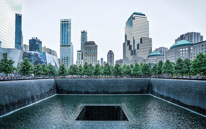 9/11 Memorial waterfall with city skyline in New York City.