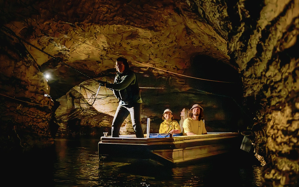 Tourists on boat exploring Te Anau Glowworm Caves in New Zealand.