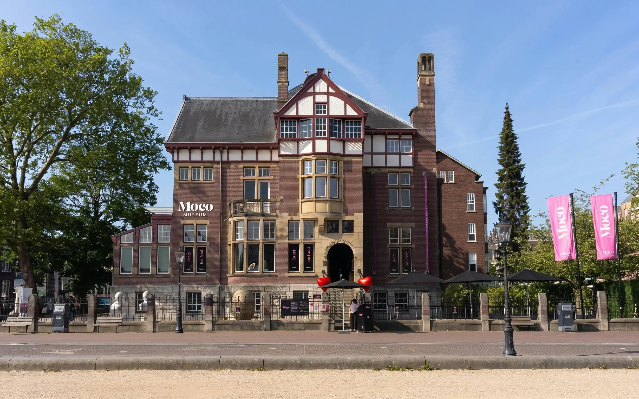 Moco Museum building in Amsterdam with pink banners and entrance steps.