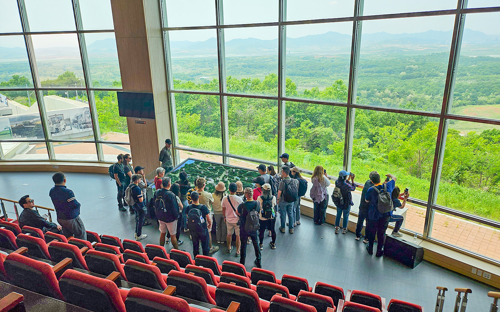 Visitors at Dora Observatory viewing North Korean landscape through large windows, DMZ.