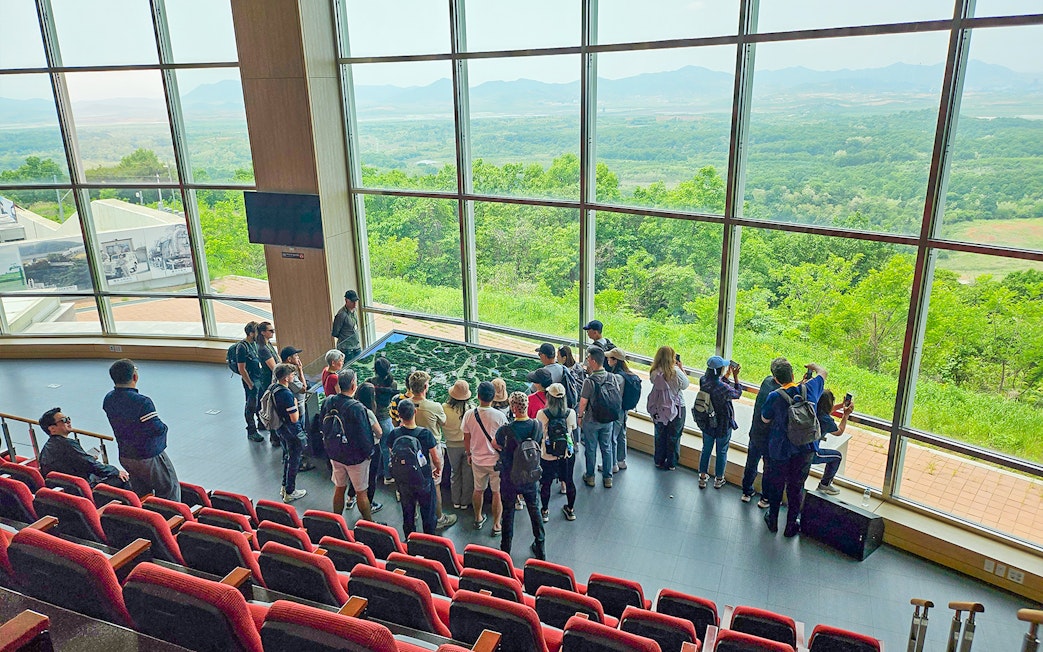 Visitors at Dora Observatory viewing North Korean landscape through large windows, DMZ.