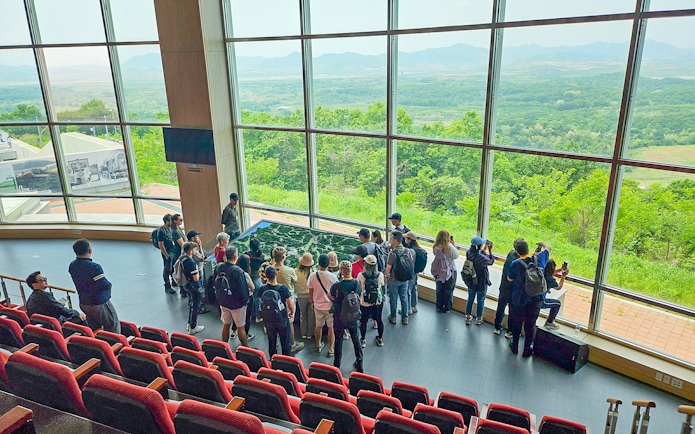 Visitors at Dora Observatory viewing North Korean landscape through large windows, DMZ.
