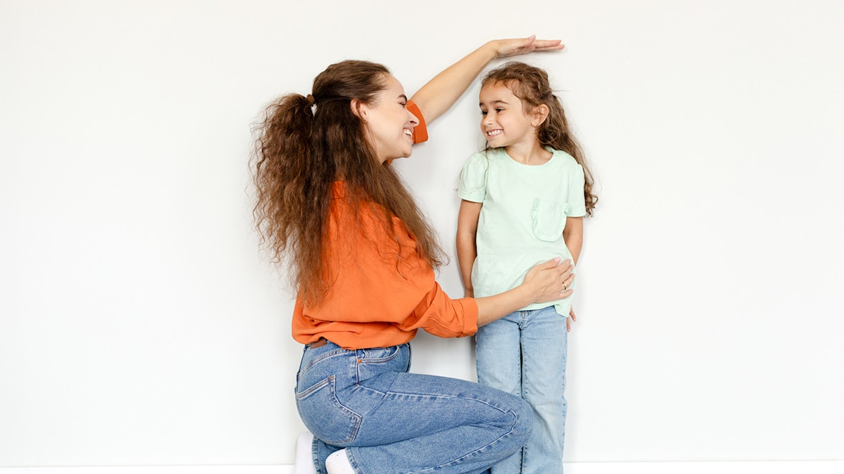 Mother measuring daughter's height against a wall.