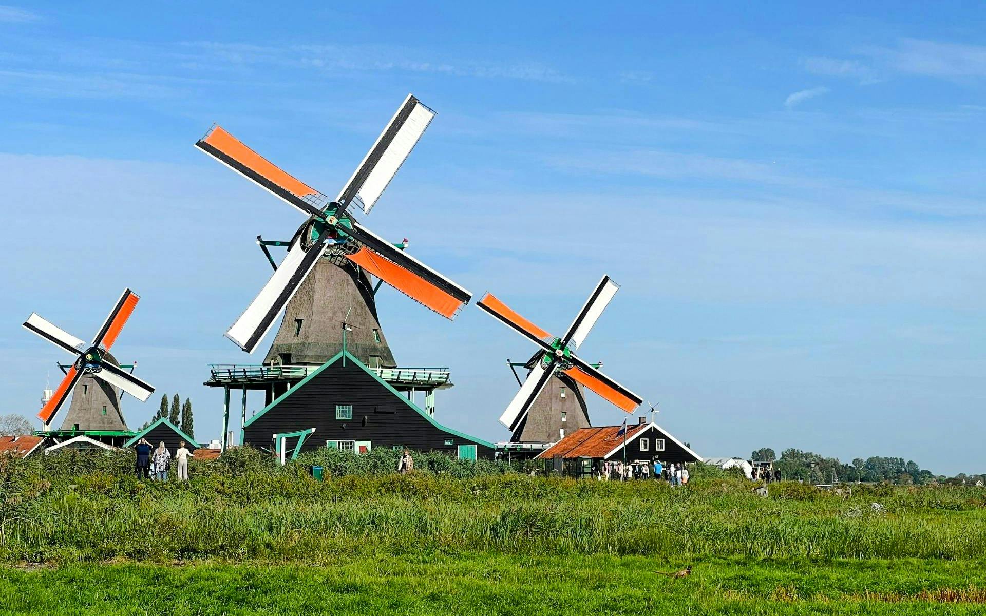 Windmills at Zaanse Schans, Netherlands, with visitors exploring the historic site.