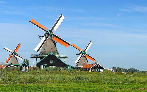 Windmills at Zaanse Schans, Netherlands, with visitors exploring the historic site.
