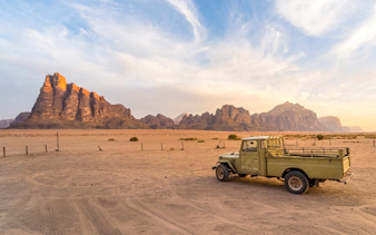 Vintage truck in Wadi Rum desert landscape, Jordan, with sandstone mountains in the background.