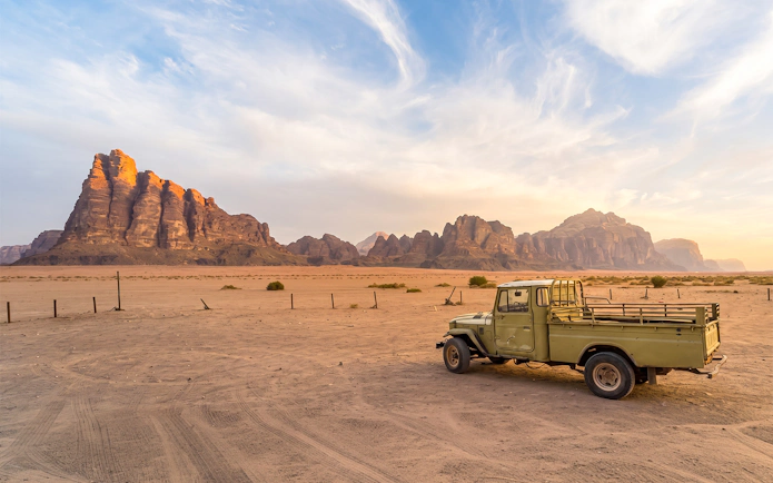 Vintage truck in Wadi Rum desert landscape, Jordan, with sandstone mountains in the background.