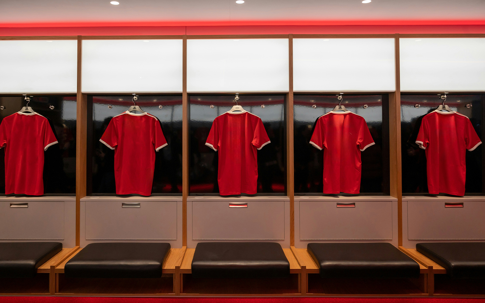 Red football jerseys hanging in a locker room.