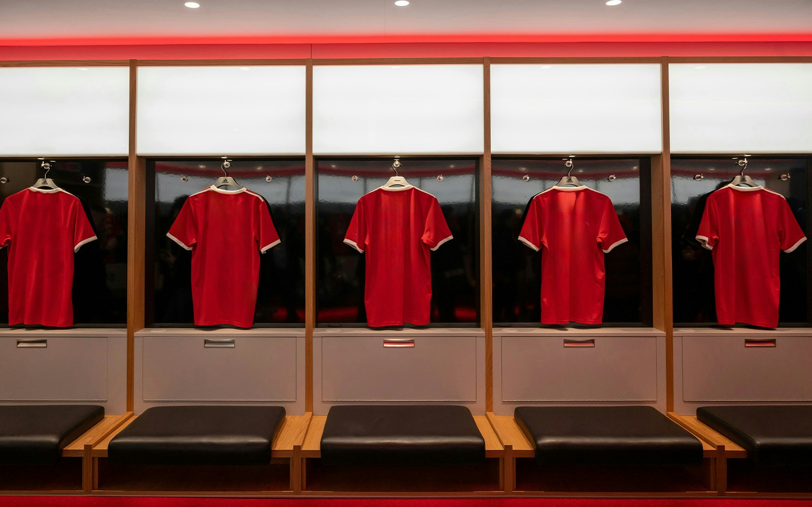 Red football jerseys hanging in a locker room.