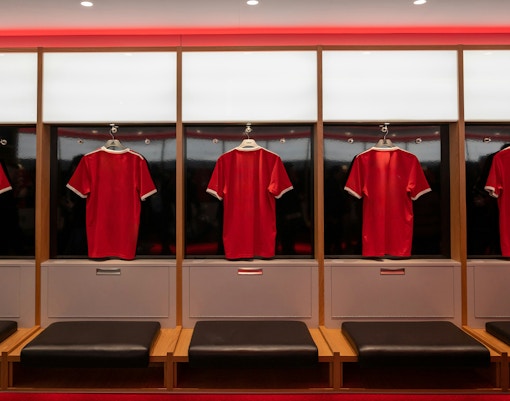 Football player locker room with jerseys and equipment in a sports stadium.