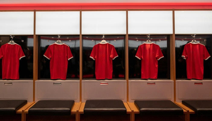 Red football jerseys hanging in a locker room.