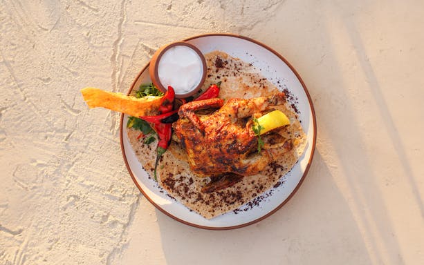 Grilled chicken with lemon and herbs on flatbread at Al Hadheerah Restaurant, Bab Al Shams.