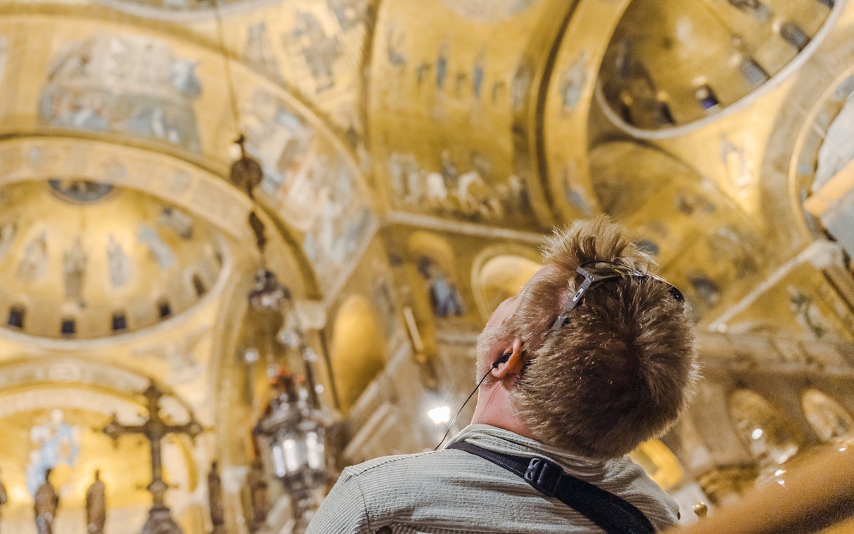 Visitor admiring golden mosaics inside St. Mark's Basilica during exclusive after-hours tour.