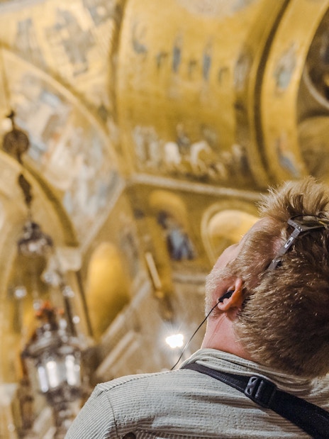 Visitor admiring golden mosaics inside St. Mark's Basilica during exclusive after-hours tour.