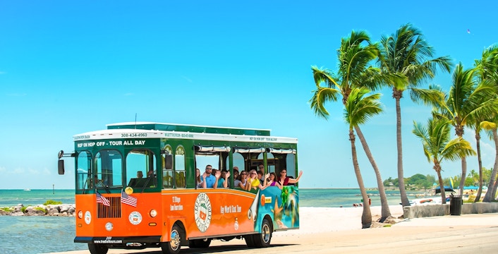 Old Town Trolley with tourists on a scenic Key West beach road.