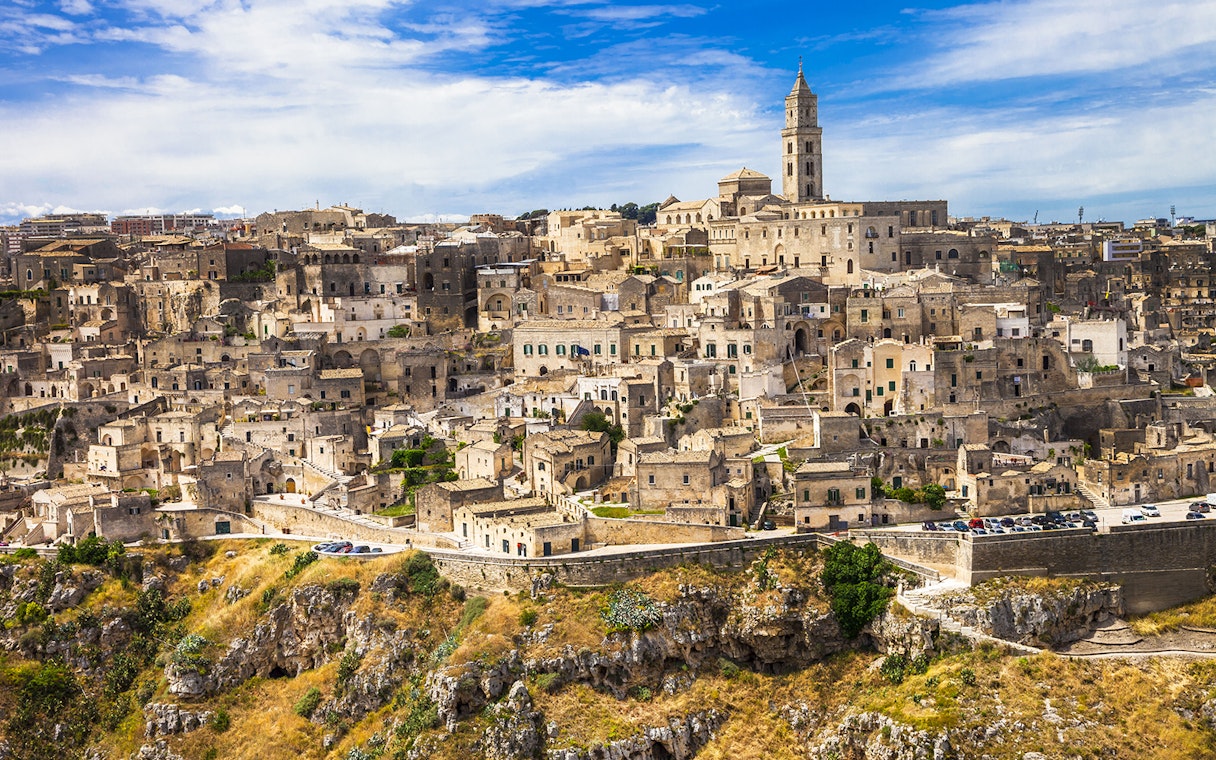 Sassi of Matera ancient stone buildings and church under blue sky.