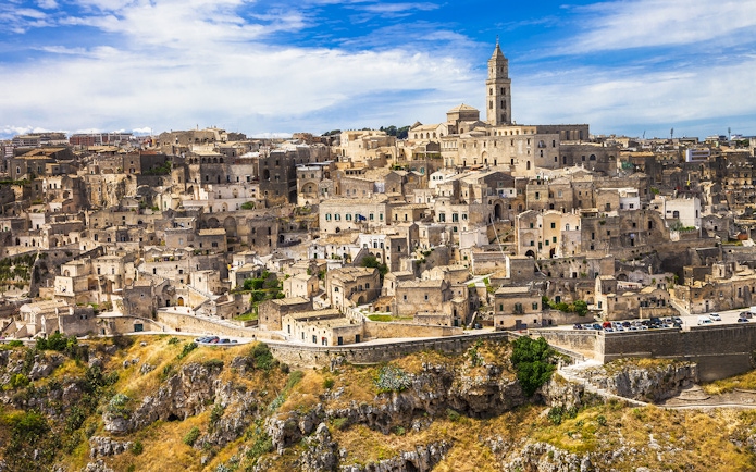 Sassi of Matera ancient stone buildings and church under blue sky.
