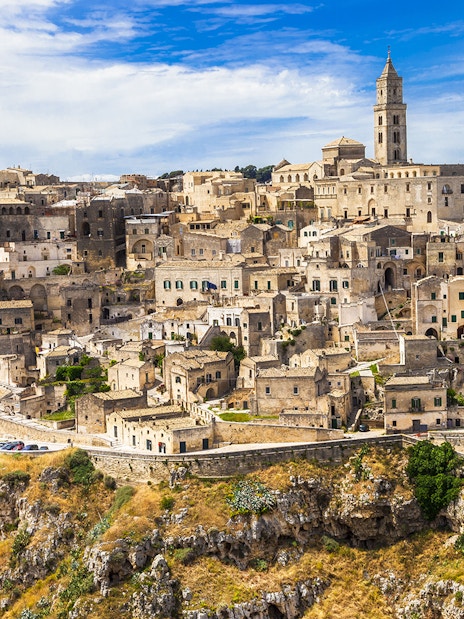 Sassi of Matera ancient stone buildings and church under blue sky.