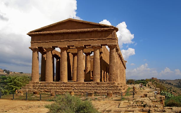 Valley of Temples, Agrigento, ancient Greek temple with columns under blue sky.